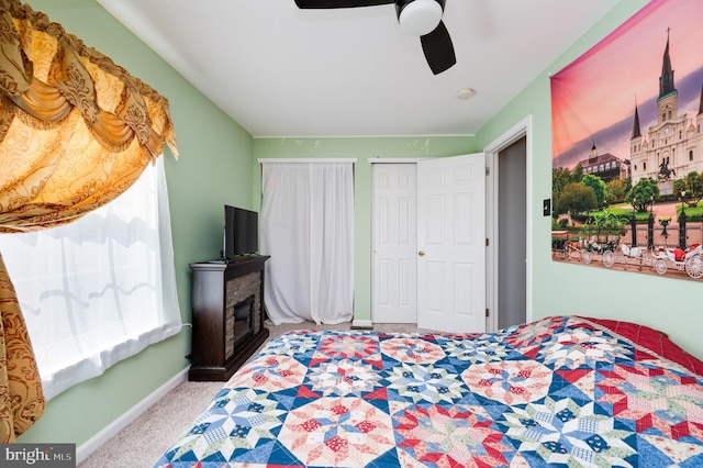 carpeted bedroom featuring baseboards, a fireplace, and a ceiling fan