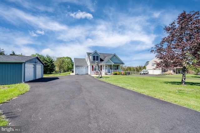view of front of home featuring an outdoor structure, a detached garage, board and batten siding, a front yard, and covered porch