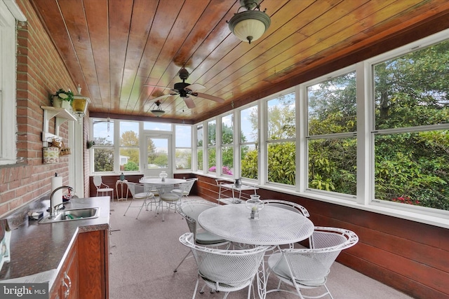 sunroom featuring outdoor dining area, a ceiling fan, and a sink
