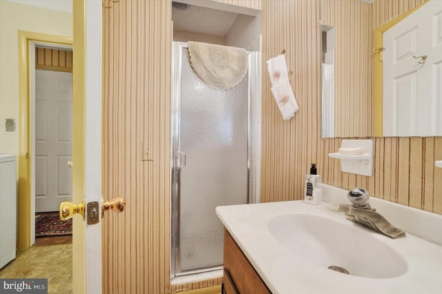 bathroom featuring vanity, wallpapered walls, and a stall shower
