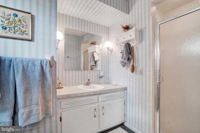 bathroom with vanity, a stall shower, and wallpapered walls