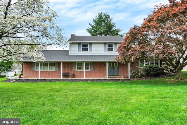 traditional-style home featuring brick siding, a shingled roof, a front lawn, and a chimney