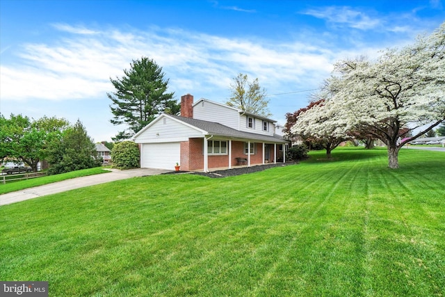 view of front facade with a garage, a front yard, a chimney, brick siding, and driveway