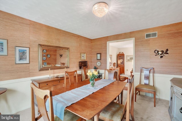 dining area with visible vents, carpet floors, and a wainscoted wall