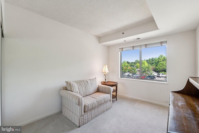 sitting room featuring a textured ceiling, baseboards, light colored carpet, and visible vents