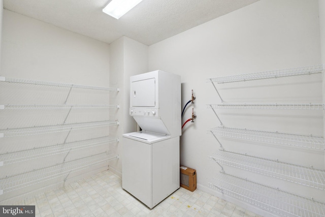 washroom featuring laundry area, stacked washer and dryer, baseboards, and light floors