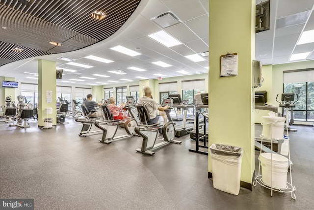 gym with a paneled ceiling and a healthy amount of sunlight