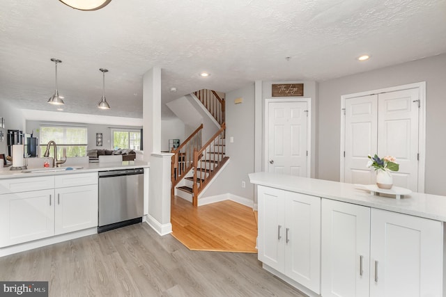 kitchen with dishwasher, a sink, light countertops, recessed lighting, and white cabinetry