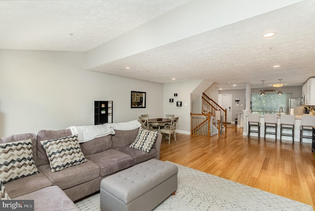 living area with baseboards, stairway, recessed lighting, a textured ceiling, and light wood-style flooring