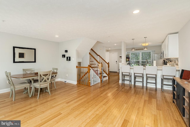 dining room with baseboards, recessed lighting, light wood-style flooring, and stairs