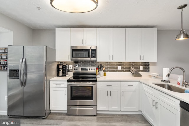 kitchen featuring white cabinetry, appliances with stainless steel finishes, a sink, and light wood-type flooring
