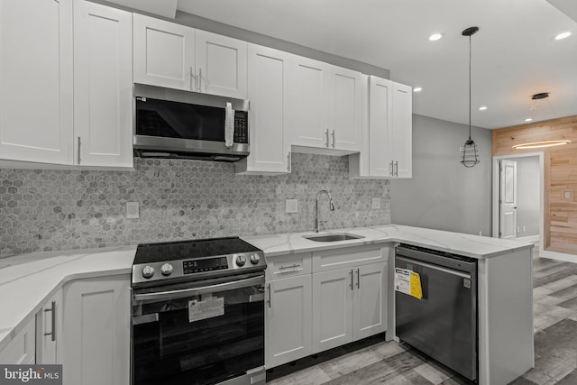 2618 N 17th St, Philadelphia, PA 19132 - kitchen featuring appliances with stainless steel finishes, light wood-type flooring, a peninsula, white cabinetry, and recessed lighting