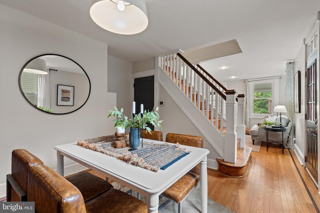 dining space featuring light wood-style flooring, stairs, and baseboards