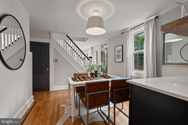 dining room featuring stairs, light wood-style floors, and baseboards