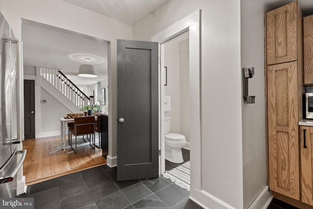 bathroom with toilet, baseboards, and tile patterned flooring