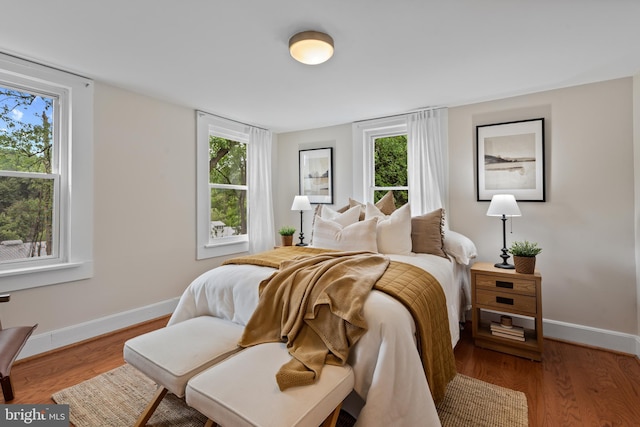 bedroom featuring multiple windows, baseboards, and wood finished floors