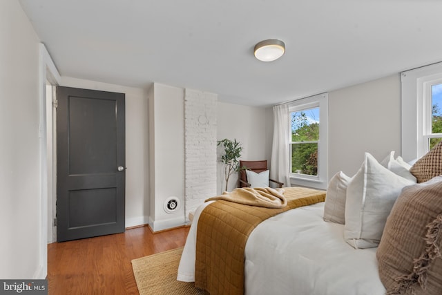 bedroom with light wood-style floors, multiple windows, and baseboards