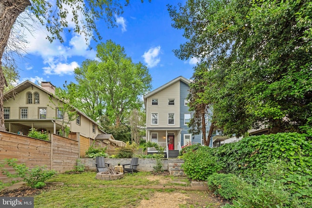 rear view of property with an outdoor fire pit, fence, and covered porch