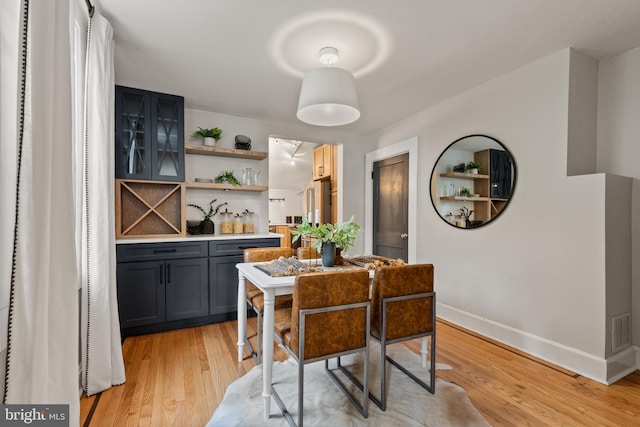 dining area featuring wet bar, baseboards, and light wood-style flooring