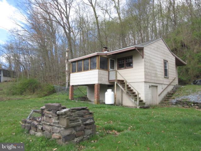 view of front of home with stairway, a front yard, a chimney, and a sunroom