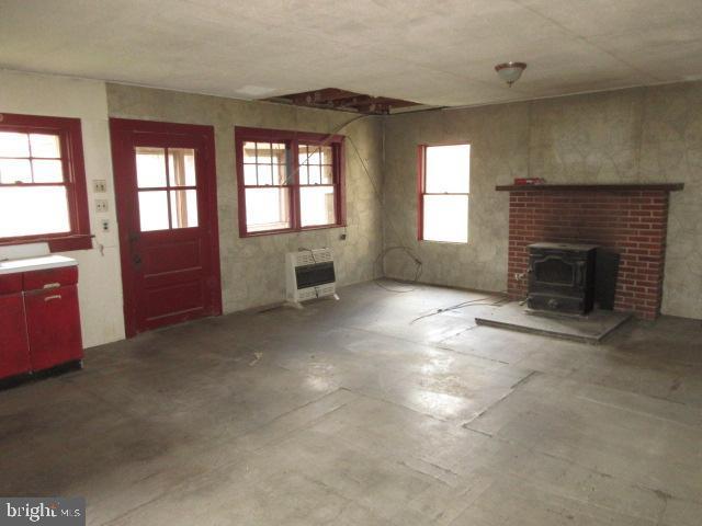 unfurnished living room with heating unit and a wood stove