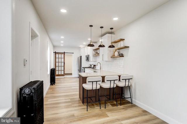 615 1st St, Lancaster, PA 17603 - kitchen featuring open shelves, a breakfast bar area, a barn door, white cabinets, and a sink