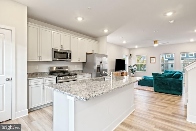 kitchen with an island with sink, stainless steel appliances, open floor plan, recessed lighting, and light wood-type flooring