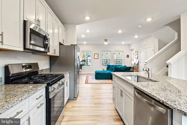 kitchen with open floor plan, recessed lighting, a sink, light wood-style flooring, and appliances with stainless steel finishes