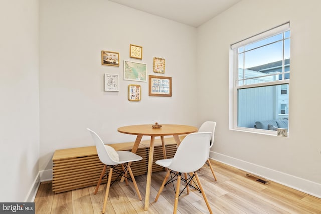 dining space with baseboards, visible vents, and wood finished floors