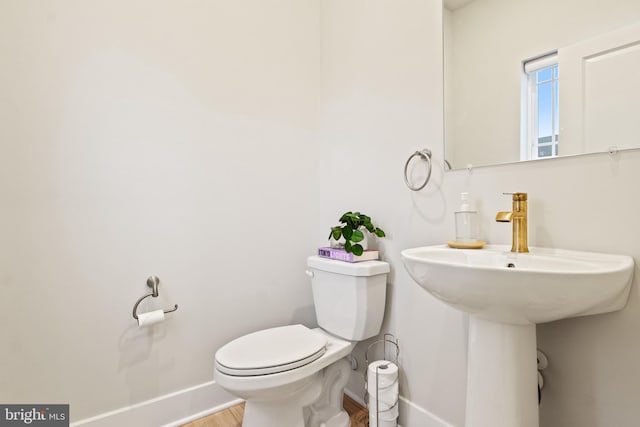 bathroom featuring baseboards, a sink, wood finished floors, and toilet