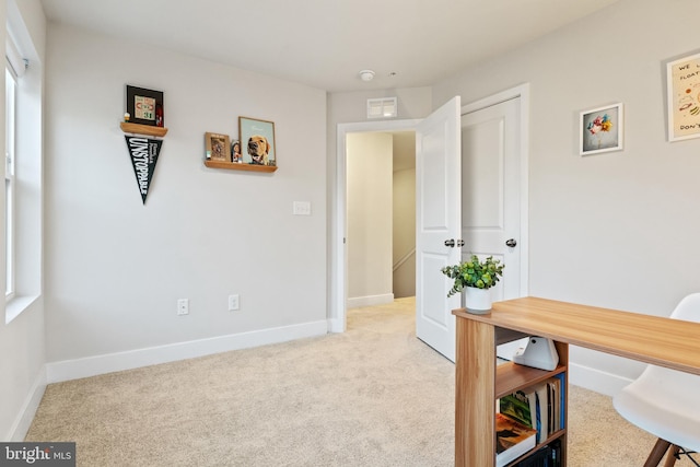 office space featuring baseboards, visible vents, and light colored carpet