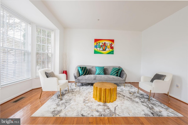 living area with baseboards, visible vents, and wood finished floors