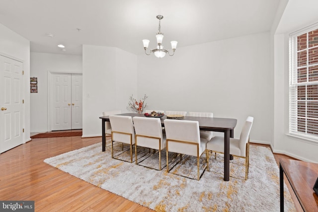 dining space featuring baseboards, an inviting chandelier, and wood finished floors