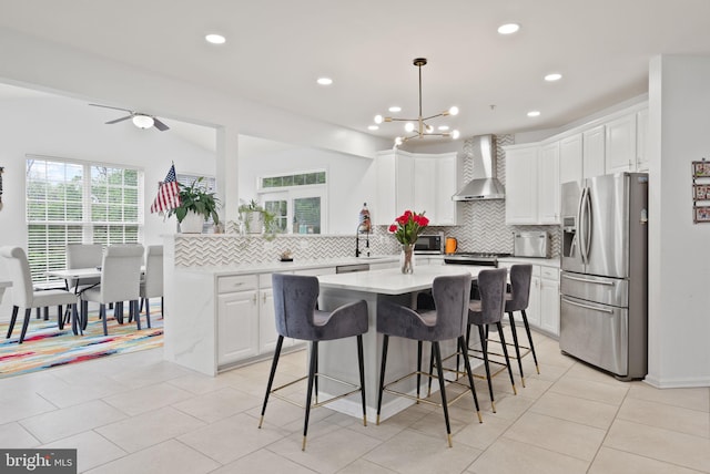 kitchen featuring appliances with stainless steel finishes, tasteful backsplash, wall chimney exhaust hood, and white cabinetry