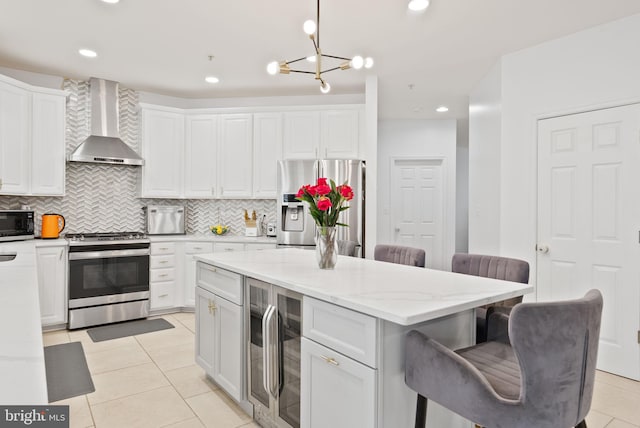 kitchen with decorative backsplash, beverage cooler, a kitchen breakfast bar, wall chimney exhaust hood, and stainless steel appliances
