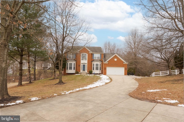 colonial-style house featuring fence, concrete driveway, a front lawn, and brick siding