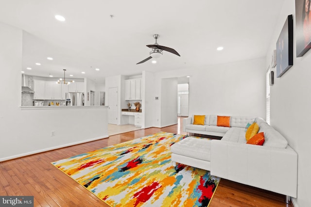 living area featuring recessed lighting, light wood finished floors, and ceiling fan with notable chandelier