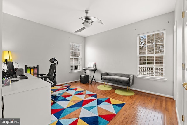 home office featuring a ceiling fan, baseboards, a wealth of natural light, and hardwood / wood-style floors