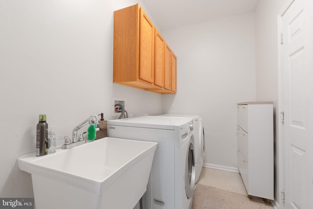laundry area with cabinet space, separate washer and dryer, baseboards, and a sink