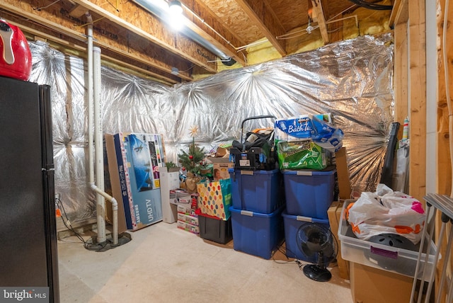 unfinished basement featuring freestanding refrigerator