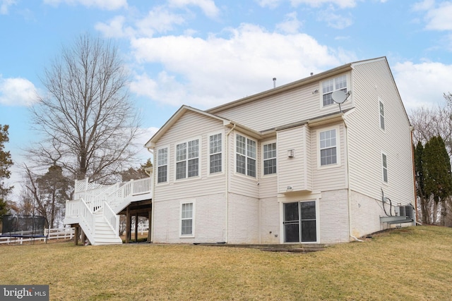 rear view of property featuring stairway, a lawn, a wooden deck, and a trampoline
