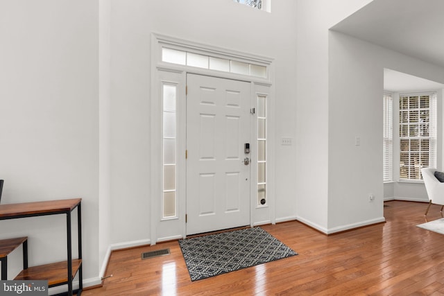 foyer with visible vents, wood-type flooring, and baseboards
