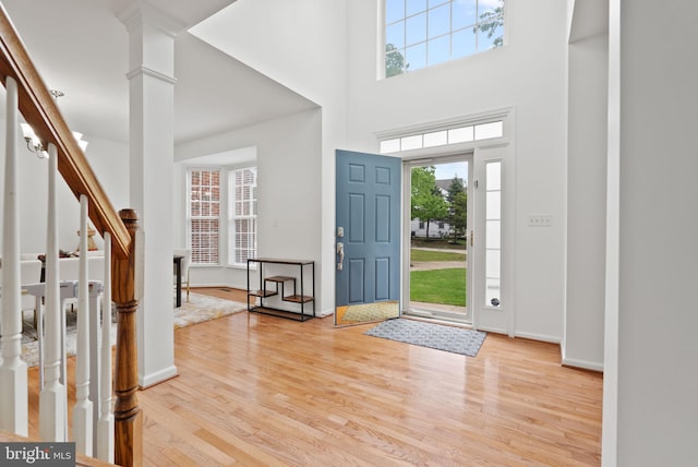 foyer entrance with baseboards, a high ceiling, light wood-style flooring, and stairs