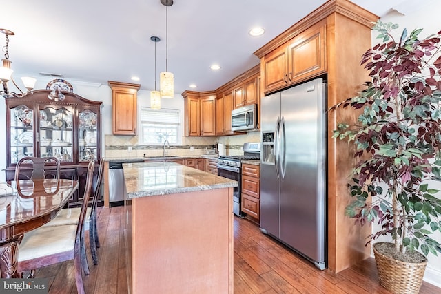 kitchen with a kitchen island, visible vents, light stone counters, wood-type flooring, and stainless steel appliances