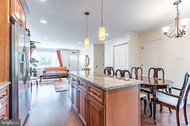 kitchen featuring an inviting chandelier, brown cabinets, dark wood-style floors, stainless steel fridge, and a breakfast bar