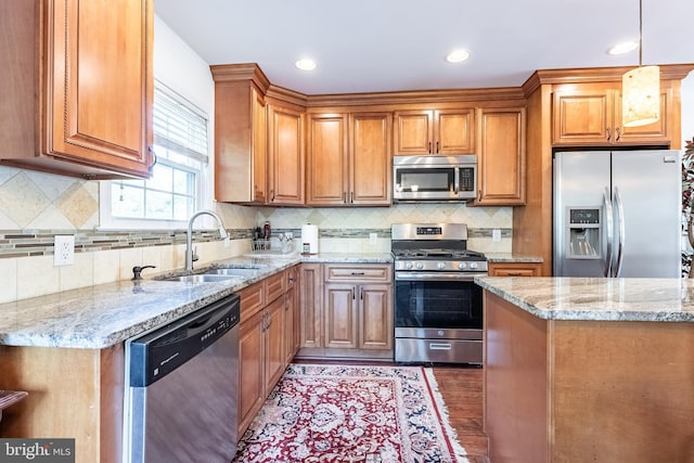 kitchen with light stone countertops, a sink, brown cabinetry, stainless steel appliances, and decorative backsplash