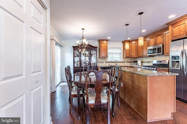 kitchen with an inviting chandelier, dark wood-style flooring, appliances with stainless steel finishes, and stone counters