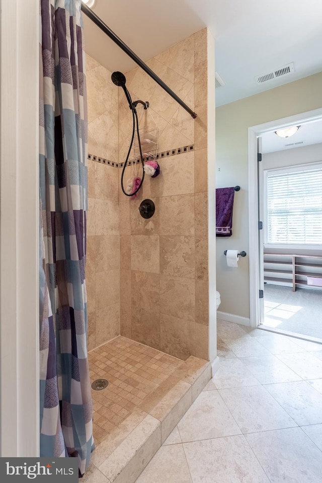 full bathroom with baseboards, visible vents, a tile shower, and tile patterned flooring