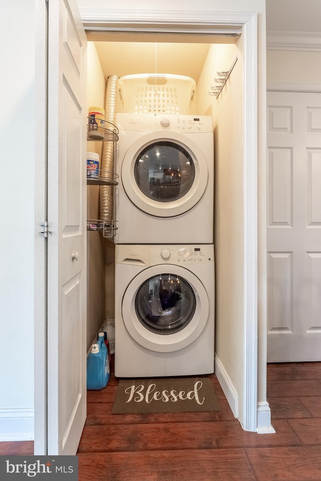 laundry room with laundry area, stacked washer and dryer, baseboards, and wood finished floors