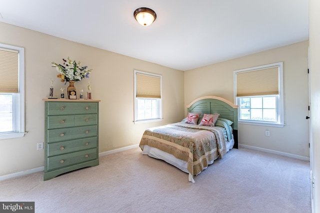 bedroom with baseboards, light colored carpet, and multiple windows